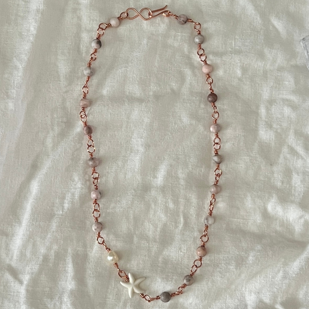 Handgjort halsband med rosa jaspisstenar och sjöstjärna på linnetyg